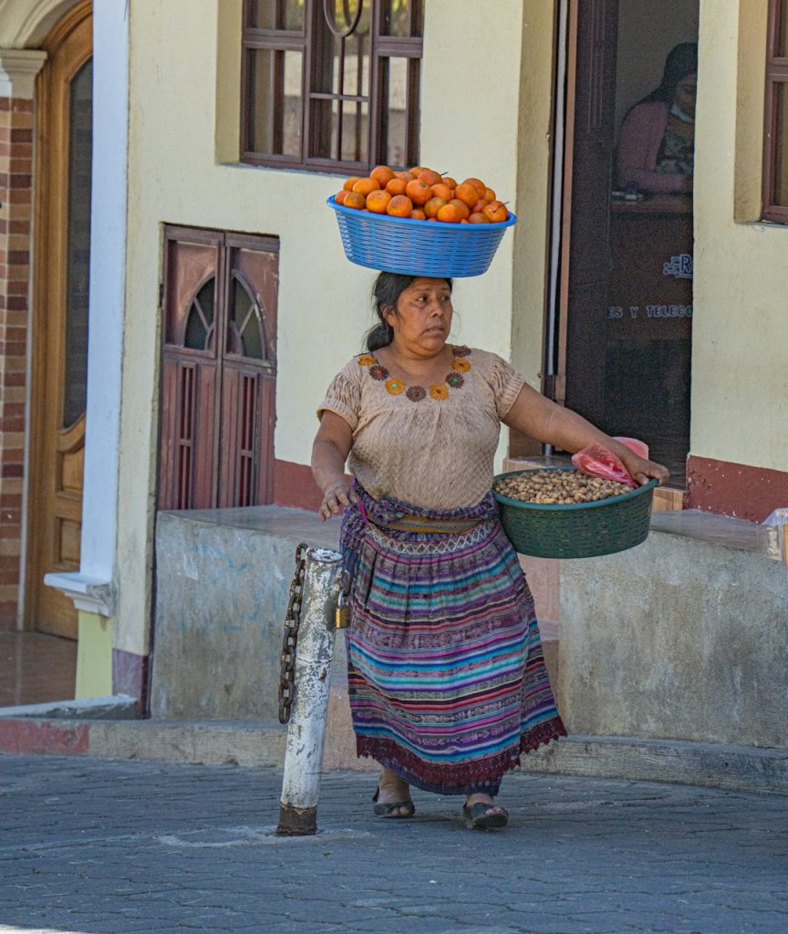 a-woman-carrying-a-basket-of-oranges-on-her-head-fb4asu8u2au